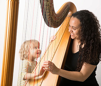 Photo of Aja playing harp with a child