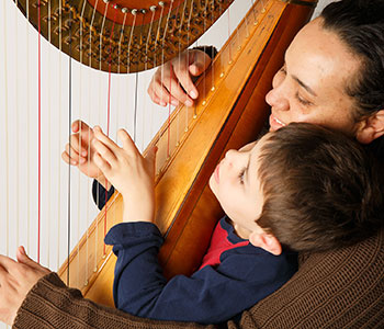 Photo of Aja playing harp with a child